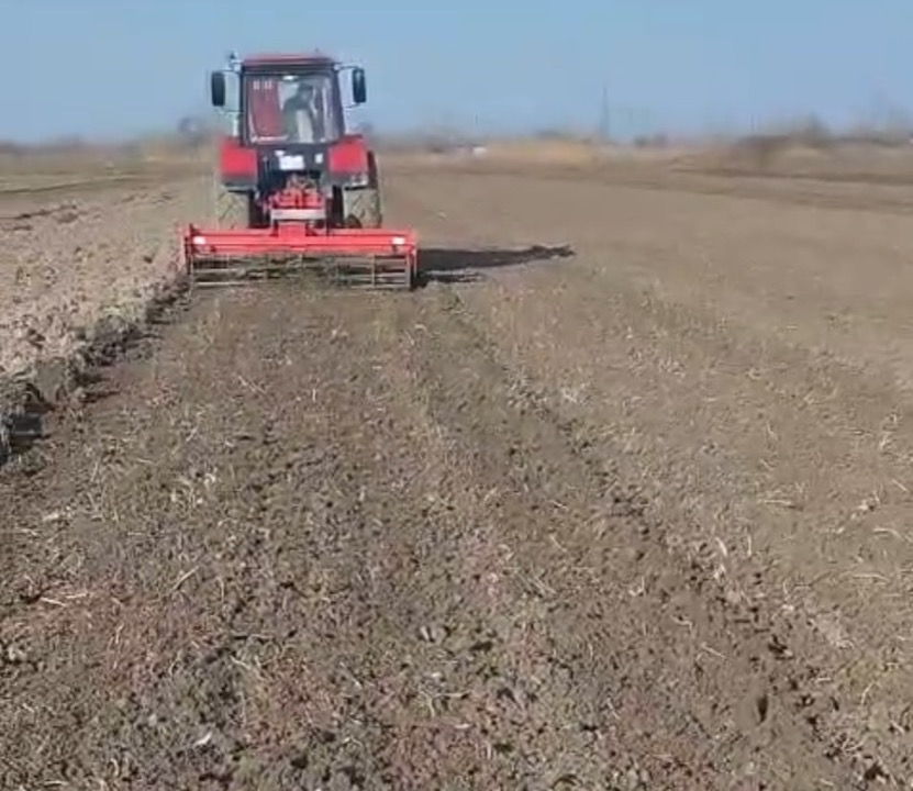 Red tractor preparing agricultural land